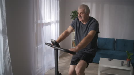 Entrenamiento-Cardiovascular-En-Bicicleta-Estática-En-Casa,-Un-Hombre-De-Mediana-Edad-Se-Preocupa-Por-La-Salud-De-Las-Actividades-Deportivas-Del-Sistema-Cardiovascular